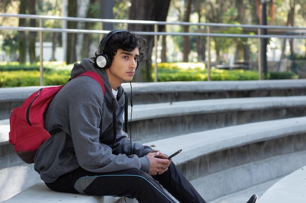 Nastoletnia studentka relaksuje się w parku słuchając muzyki przez słuchawki