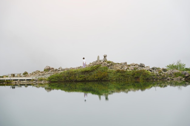 Zdjęcie nastoletnia szczęśliwa podróżniczka szuka mgły w górach z jeziorem ludzie z krajobrazem