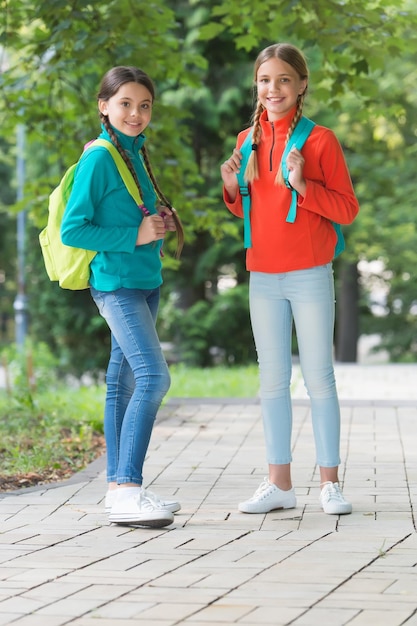 Nastoletnie dzieci z plecakiem koncepcja przyjaźni najlepsi szkolni przyjaciele chodzą do szkoły z zabawą uczennice z plecakiem nastolatki z plecakami spacerują w parku Powrót do szkoły