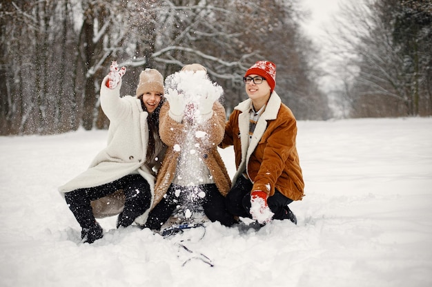 Nastoletnie rodzeństwo i ich matka jeżdżą na sankach w parku zimowym