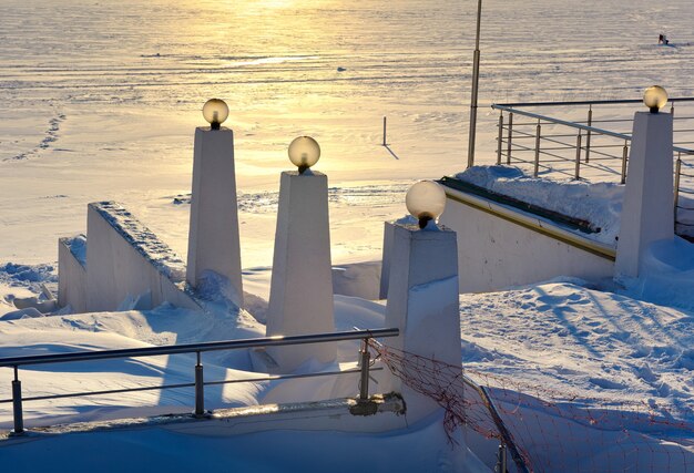 nasyp zimowy o zachodzie słońca balustrada schodów ze słupami oświetleniowymi