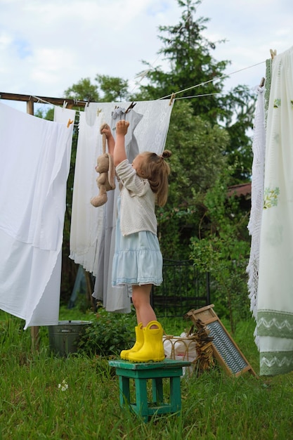 Natura bawi się pod otwartym niebem. Wesoła dziewczyna cieszy się zabawą, naśladując dzień prania.