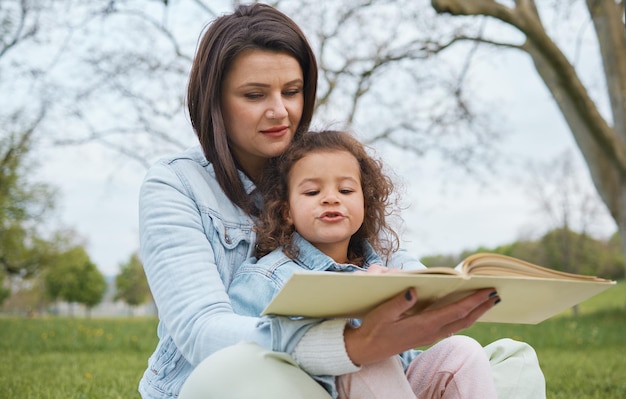 Natura matka i dziecko czytają książkę w parku czas na historię w parku lub ogrodzie w letni weekend Opowiadanie książek i kochająca mama uczy dziewczynę czytać siedząc na trawie na podwórku i razem odpocząć