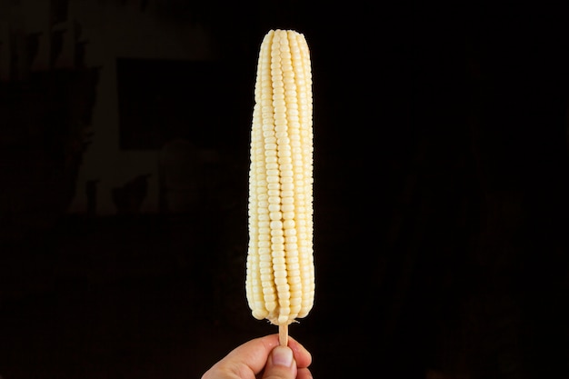 naturalna biała kukurydza na kolbie gotowana na czarnym tle