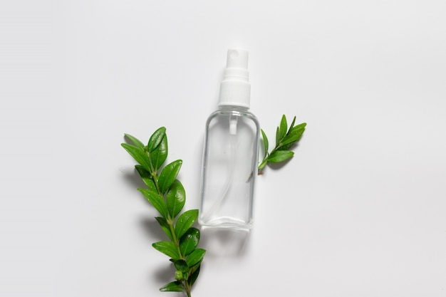 Naturalna kosmetyczna plastikowa butelka z cieczem i zielenią opuszcza na szarym tle.