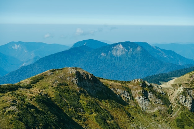 Naturalna Tapeta Z Wysokimi Górami We Mgle I Zielonym Wzgórzem