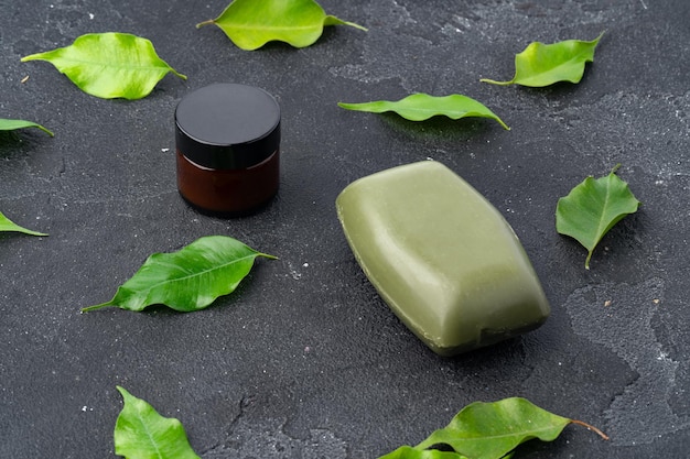Zdjęcie naturalne mydło i zielone liście na ciemnoszarym tle