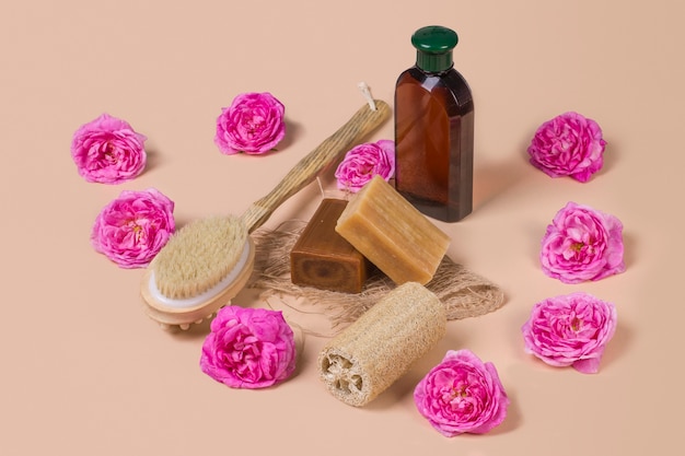 Naturalne mydło loofah loofah i butelka produktu kosmetycznego na beżowym tle z różami