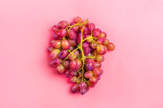 Zdjęcie naturalne organiczne czarne soczyste winogrona na powierzchni trendu różowy widok z góry flat lay