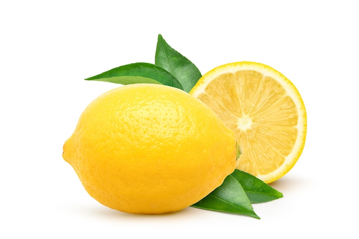Zdjęcie naturalne owoce cytryny z pokrojoną na pół i zielonym liściem na białym tle.