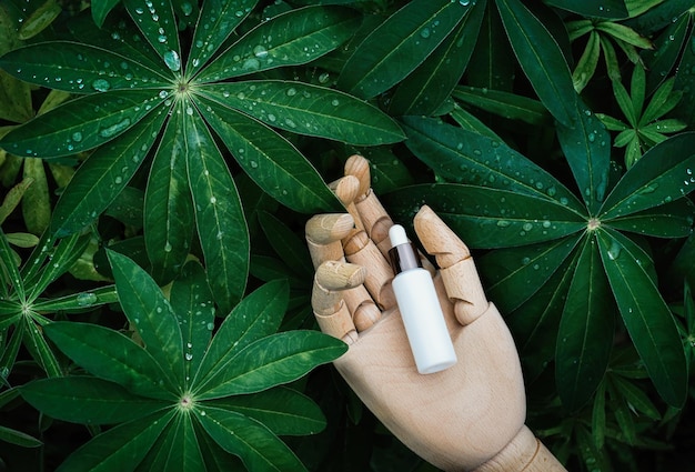 Naturalne serum kosmetyczne na drewnianej dłoni w tle zielonych roślin