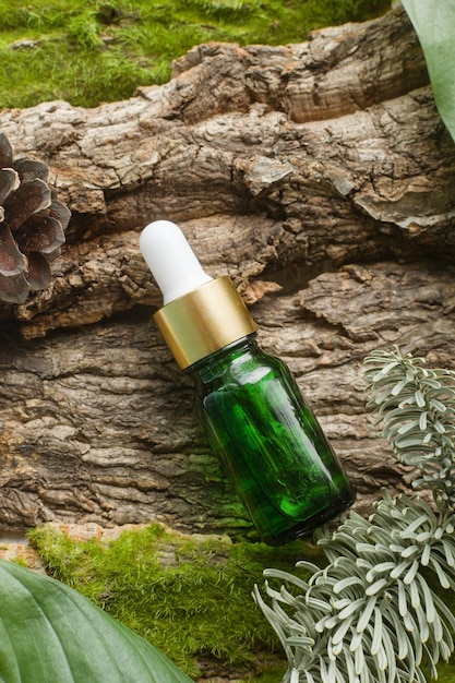 Naturalne serum w szklanej butelce kosmetycznej z olejkami aloesowymi witaminami leży na naturalnym leśnym mchu