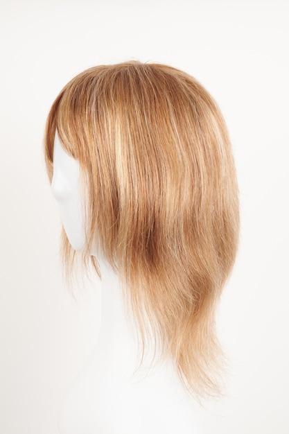 Naturalnie wyglądająca blond jasna peruka na białej głowie manekina Włosy średniej długości strzyżone na plastikowym uchwycie peruki izolowanym na białym tle widok z boku