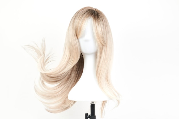 Naturalnie wyglądająca blond peruka na białej głowie manekina Długie włosy na plastikowym uchwycie na perukę odizolowanym na białym tle, widok z przodu