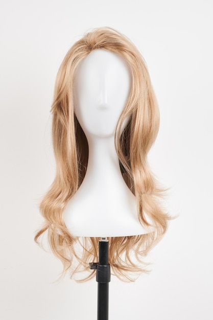 Naturalnie wyglądająca blond peruka na białej głowie manekina Długie włosy na plastikowym uchwycie peruki izolowane na białym tle widok z przodu