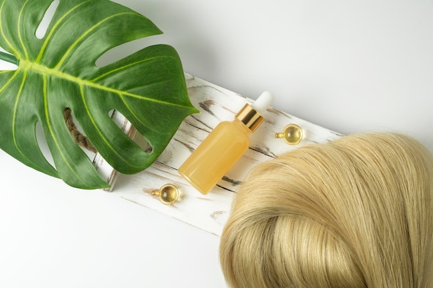 Zdjęcie naturalny olejek lub serum do pielęgnacji włosów leżący na białej drewnianej tacy koncepcja pielęgnacji i wygładzania włosów