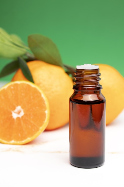Naturalny organiczny olejek eteryczny z pomarańczy do pielęgnacji skóry twarzy i ciała Nawilżająca aromaterapia leczenie detoksykacyjne efekt antystresowy Świeże owoce zielone liście zielone tło