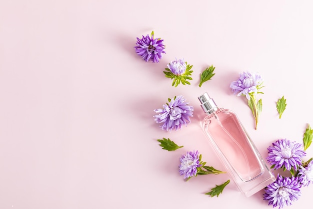 Naturalny produkt kosmetyczny w szklanej butelce na różowym tle i jesienne kwiaty prezentacja miejsca na perfumy na tekst