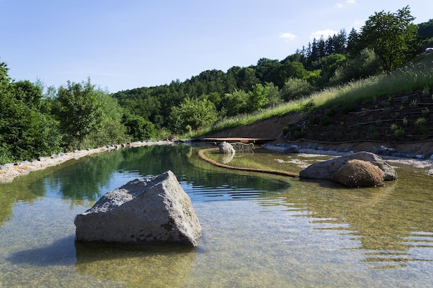 Naturalny staw kąpielowy oczyszczający wodę bez chemikaliów przez filtry i rośliny