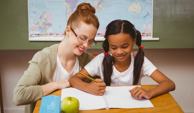 Nauczyciel pomaga dziewczyna z pracą domową w sala lekcyjnej