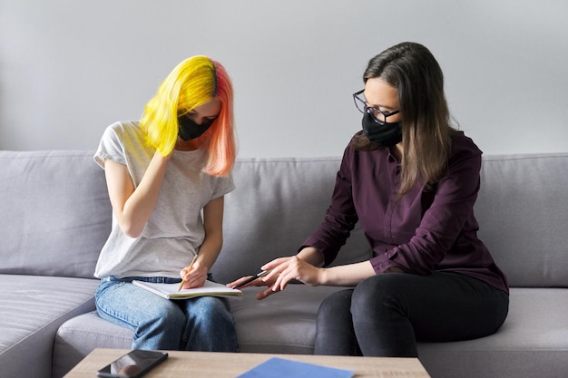 Zdjęcie nauczyciel pracujący ze studentem w czarnych maskach ochronnych