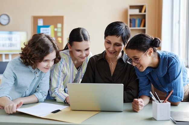 Nauczyciel za pomocą laptopa razem z dziećmi