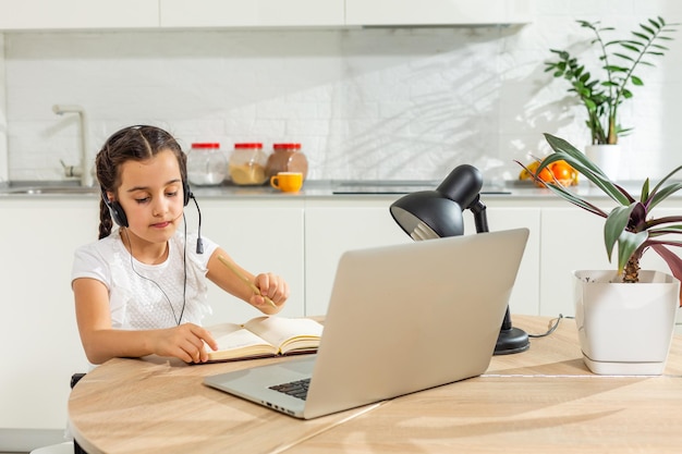 Nauka na odległość dla dzieci. Śliczna mała dziewczynka za pomocą laptopa w domu. Edukacja, nauka online, nauka w domu, technologia, nauka, przyszłość, nauka na odległość, praca domowa, koncepcja stylu życia dzieci uczennicy.