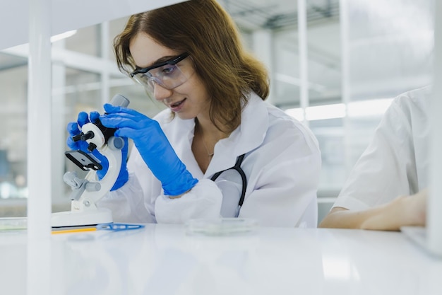 Nauka, technologia, chemik opracowujący koncepcję, badaczka, naukowiec medyczny, lekarz lub student patrzący w mikroskop w nowoczesnym laboratorium.