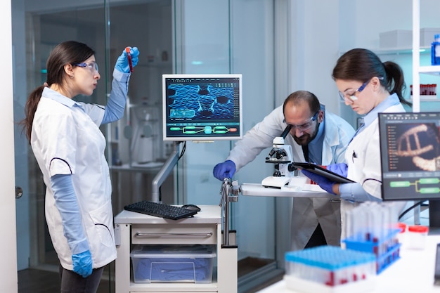 Naukowcy pracujący na monitorze ze sprzętem medycznym analizującym krew, próbki materiału genetycznego