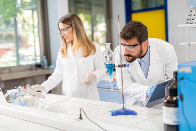 Naukowcy pracujący z niebieską cieczą w lejku rozdzielającym w laboratorium