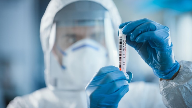 Zdjęcie naukowiec medyczny noszący rękawiczki chirurgiczne, maskę twarzy i osłonę trzyma rurkę testową z próbką krwi i odczytem etykiety w laboratorium mikrobiologicznym ds. rozwoju leków i szczepionek na covid-19