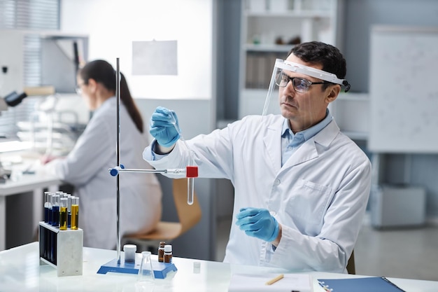 Naukowiec noszący sprzęt ochronny i osłonę twarzy w laboratorium