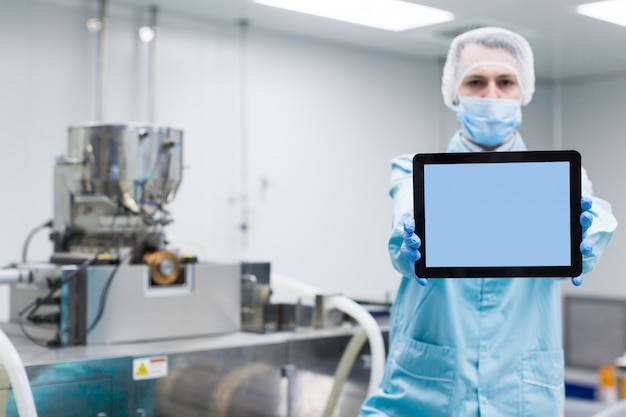 Naukowiec pokazuje pustą tabletkę w pobliżu maszyn