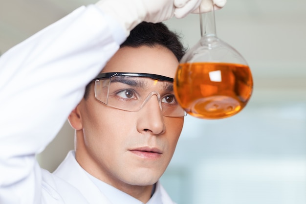 Zdjęcie naukowiec stojący w laboratorium i trzymający zlewkę