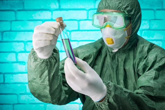 Naukowiec w rękawiczkach ochronnych i okularach szuka i testuje chemikalia w probówkach w laboratorium