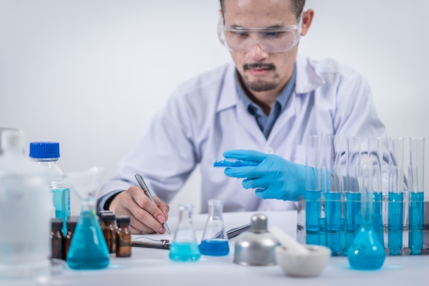 Naukowiec ze sprzętem i eksperymentami naukowymi, szkło laboratoryjne zawierające płyn chemiczny do projektowania lub ozdabiania nauki lub innych treści