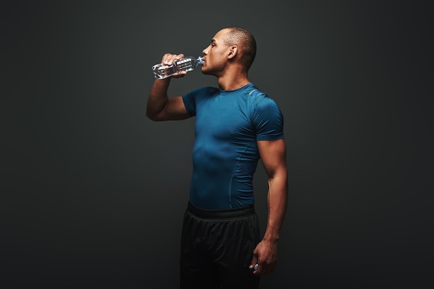 Nawadnianie umięśnionego sportowca pijącego wodę po treningu