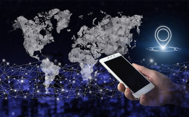 Nawigacja, mapa i innowacje. Ręka trzymać biały smartphone z cyfrowym hologramem świat, ziemia, mapa, znak znacznika lokalizacji na ciemnym tle niewyraźne miasta. Mapa GPS, lokalizacja adresu pin w aplikacjach mobilnych.