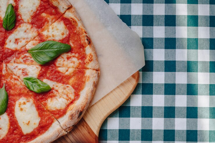 Zdjęcie neapolitańska pizza z szynką, serem, rukolą, bazylią, pomidorami posypanymi serem na desce