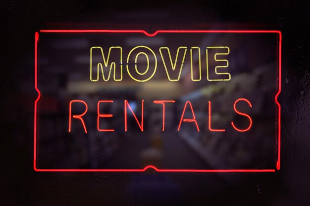 Zdjęcie neon movie rentals sign w mokrym deszczowym oknie
