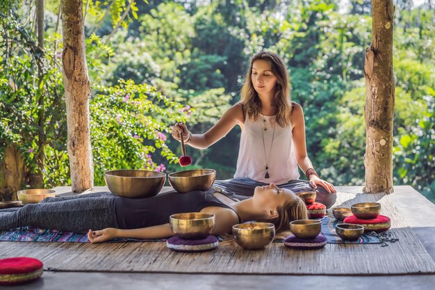 Nepal budda miedziana miska do śpiewania w salonie spa młoda piękna kobieta robi masaż terapeutyczny śpiewający