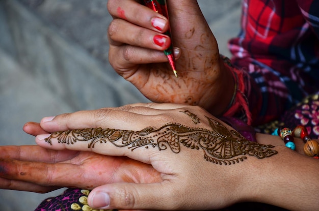 Zdjęcie nepalska dziewczyna artysta używa henną tuszu napisz rysunek farbę mehndi tatuaż z henny jako wzór sztuki ciała na ręce podróżnych tajskie kobiety ludzie między podróżą wizyta na rynku starego miasta thamel w katmandu nepal