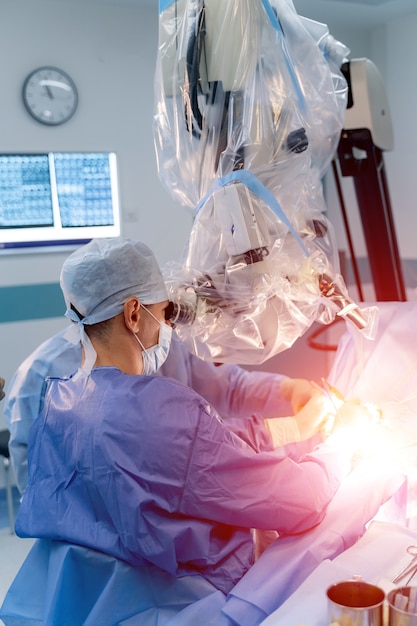 Neurourgeon operuje zrobotyzowanym urządzeniem do chirurgii medycznej. Sterowanie ręczne za pomocą minimalnie inwazyjnego systemu chirurgicznego. Selektywne skupienie z boku. Operacja na mózgu.