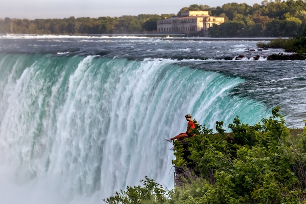 Niagara Falls Kanada Młode kobiety siedzące na krawędzi i patrzące na wodospad