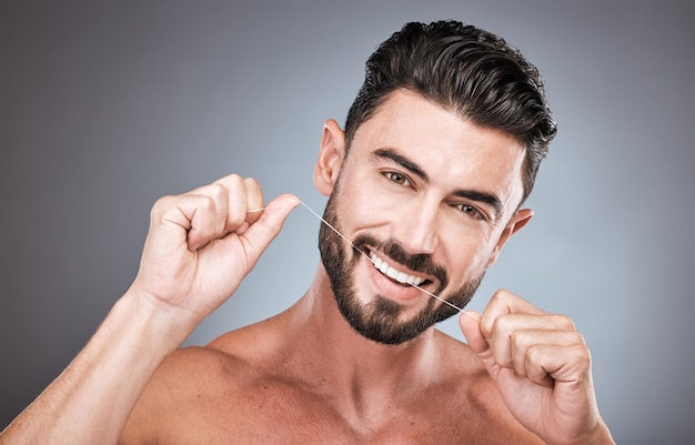 Nić dentystyczna wellness i portret mężczyzny w studio dla piękna zdrowego ciała i higieny na tle Męski model nitkowanie zębów i czyszczenie ust dla uśmiechu twarzy świeży oddech i szczęśliwe zęby