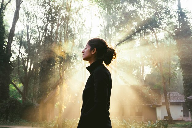 Nie do poznania kobieta stojąca przed niesamowitym wschodem słońca w lesie. Park Narodowy w Tajlandii. Trekking i turystyka w Azji. Nowe doświadczenie w kontakcie z naturą. Zdrowy duchowy styl życia.