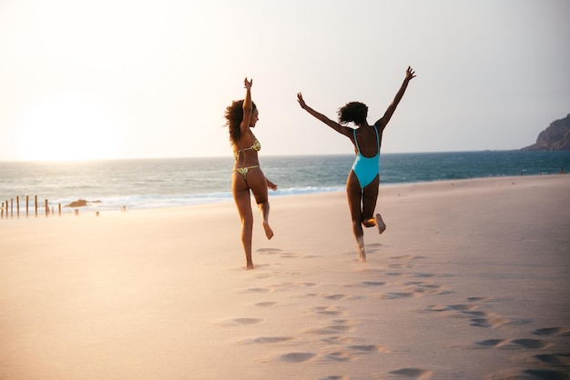 Nie do poznania kobiety bawiące się na plaży w stroju kąpielowym