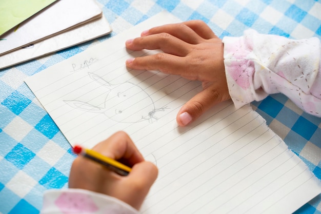 Nie do poznania leworęczne dziecko rysujące królika z kreskówki na kartce papieru. Mała dziewczynka trzyma ołówek i bada kreatywność. Koncepcja wypoczynek dla dzieci. Styl życia z dziećmi w domu.
