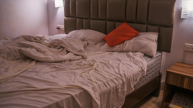 Nie pościelone łóżko w nowoczesnej sypialni Z góry ciepły koc i miękkie poduszki umieszczone na wygodnym nieposłanym łóżku w stylowej nowoczesnej sypialni