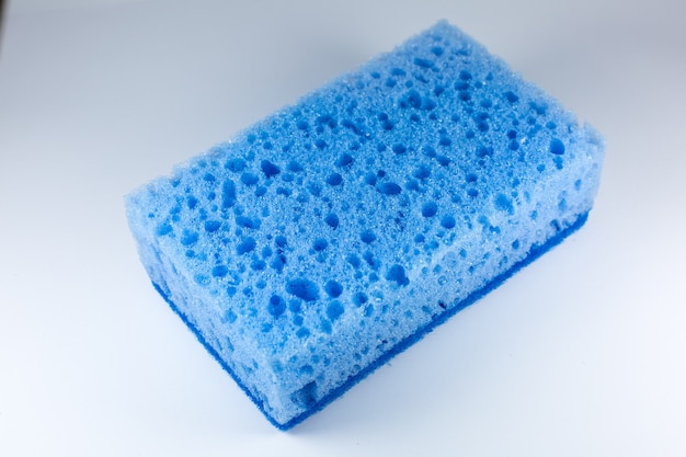 Niebieska gąbka do mycia naczyń na białym tle. Sztuczne włókno nie jest narzędziem przyjaznym dla środowiska. Rzeczy do kuchni.